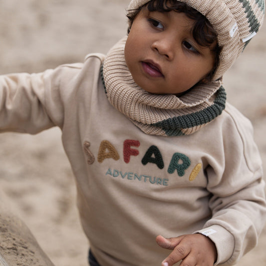 Kind trägt Little Dutch Pullover Sandbeige im Freien
