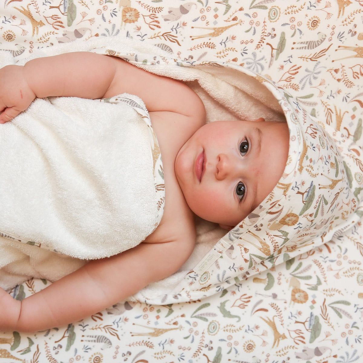 Baby eingewickelt in Little Dutch Badeponcho Safari Wonders