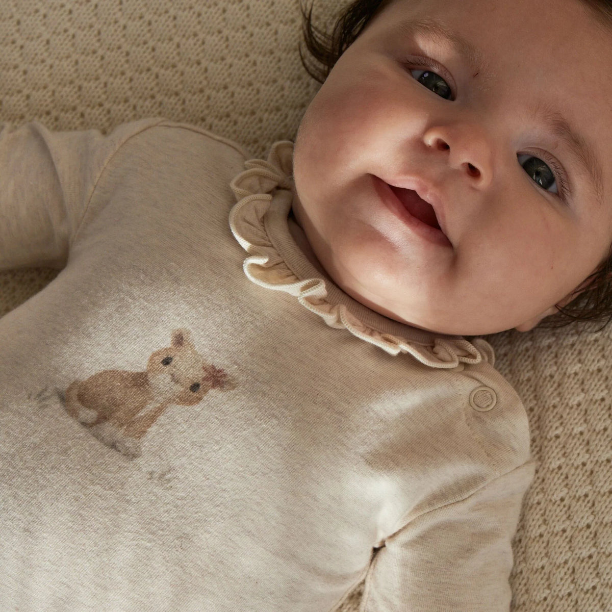 Baby trägt Little Dutch Babybody aus Baumwolle Bio mit Löwin-Print und Rüschen