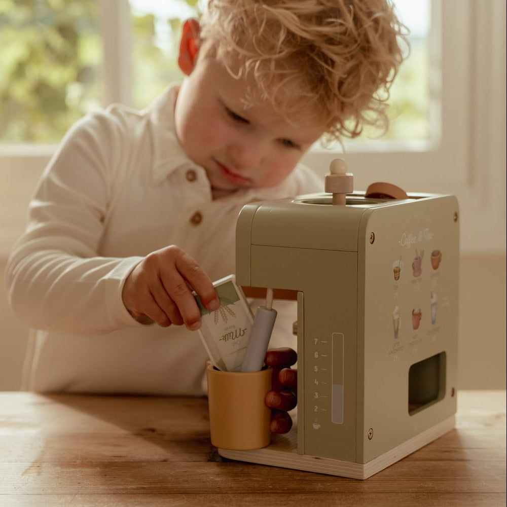 Rollenspiel - Kind hält den Spiel-Milchkarton über die gelbe Milchkanne neben der grünen Little Dutch Kaffeemaschine.
