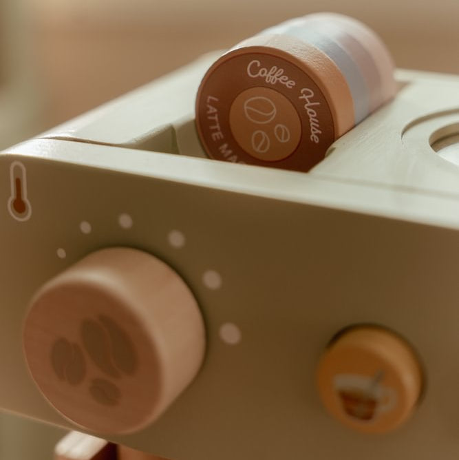Nahaufnahme der farbigen Spielkapseln auf der grünen Little Dutch Kaffeemaschine und des großen Drehknopfs an der Vorderseite.