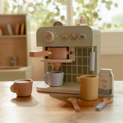Little Dutch Kaffeemaschine auf einem Holztisch mit zwei Tassen, gelber Milchtüte, Milchkarton und Löffeln.
