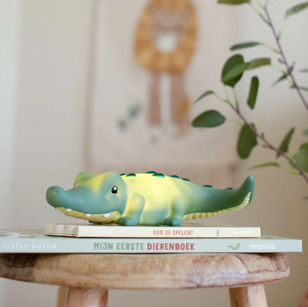Grünes Little Dutch Krokodil-Nachtlicht mit sanftem Licht auf einem Bücherstapel